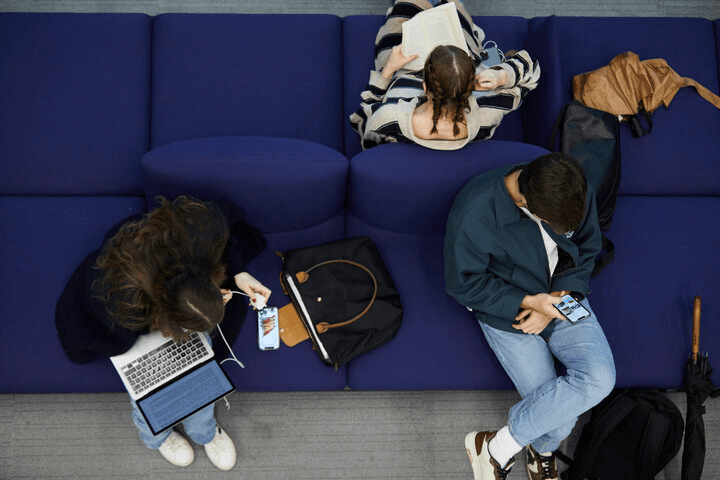 IE students sitting in a blue sofa, photographed from above