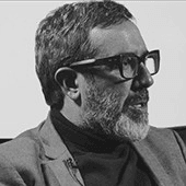 Black and white photo of a bearded man wearing glasses and a turtleneck, looking to the side.