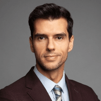 A professional portrait of a man in a dark suit and blue tie.