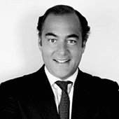 A black and white portrait of a smiling man in a suit and tie.