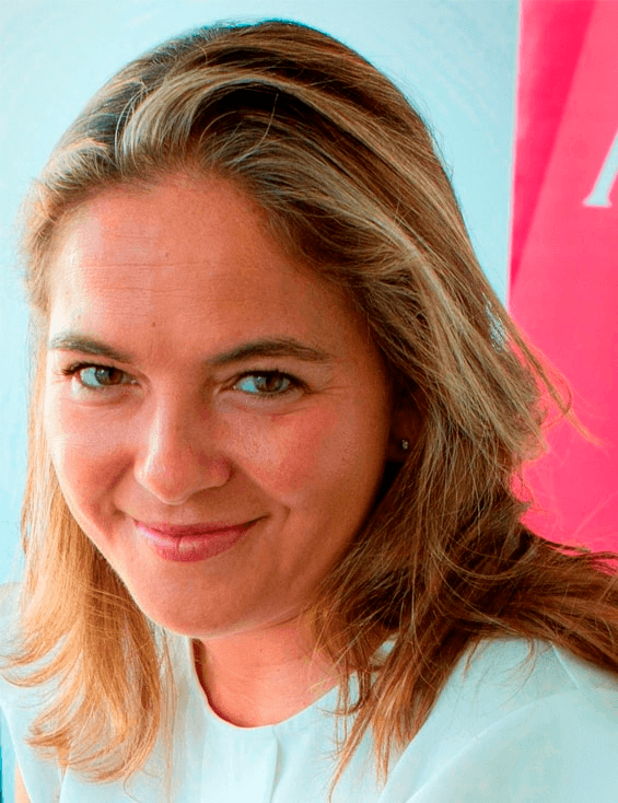 A woman smiling at the camera with a blurred background.