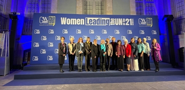 A group of women standing together at an event promoting female leadership in the UN.
