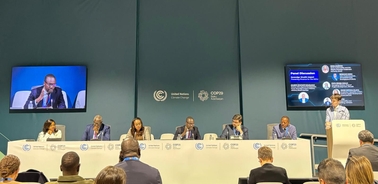 A panel discussion taking place at a conference with several speakers and an audience.