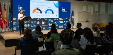 A woman presents statistical data to an audience in a conference room at a university event.