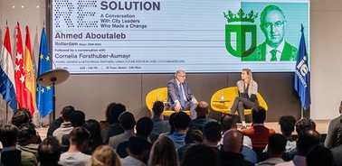 A conference event featuring a discussion between two speakers and an audience.