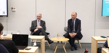 Two men seated in a professional setting during a discussion.