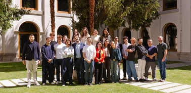 A diverse group of people gathered in a courtyard surrounded by trees and a building.