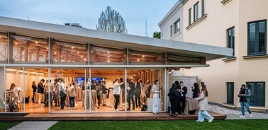 A modern event space filled with people socializing during an evening gathering.
