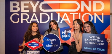 A group of four young women celebrate their graduation with signs promoting their future as alumni.