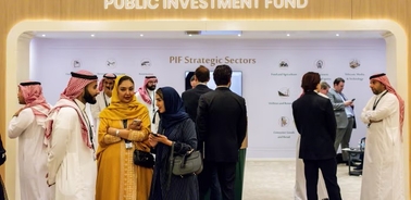A group of people engages in conversation at a conference for the Public Investment Fund.
