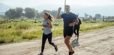 A group of people running along a dirt path in a scenic outdoor setting.