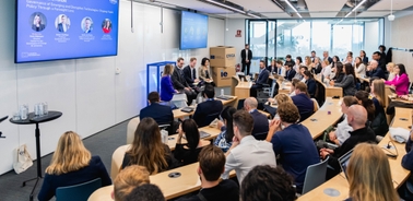 A panel discussion taking place in a modern conference room with an audience engaged in the presentation.