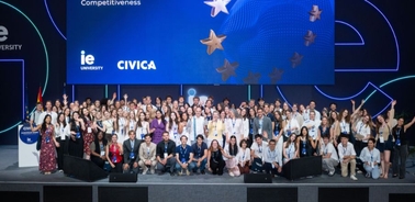 A large group of people gathered at an event, with a backdrop featuring the logos of IE University and CIVICA.