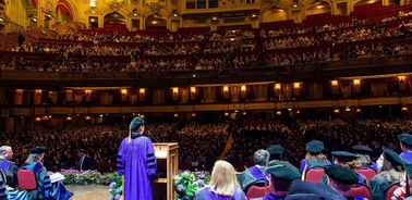 A graduation ceremony taking place in a grand theater with a large audience.