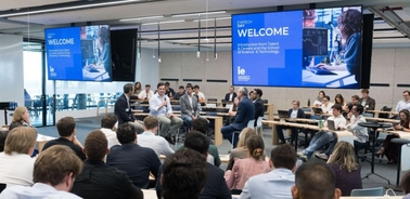 A conference or seminar in a modern setting with an audience engaged in a discussion.