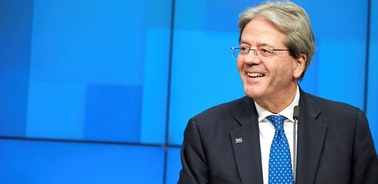 A smiling man in a suit and tie against a blue background.