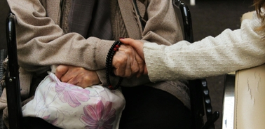 Two people holding hands, one of whom is in a wheelchair