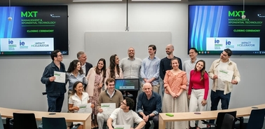 A group of people gathered for a closing ceremony, holding certificates in a modern classroom setting.