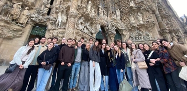 A group of people posing in front of an intricately carved stone façade.
