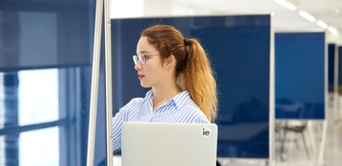 A woman is working on a laptop in a modern office environment.