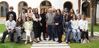 A diverse group of people posing for a photo on a grassy courtyard with a building in the background.