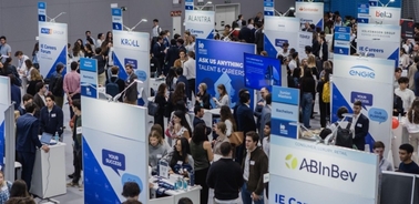 A busy job fair event with various company booths and people engaging in conversations.