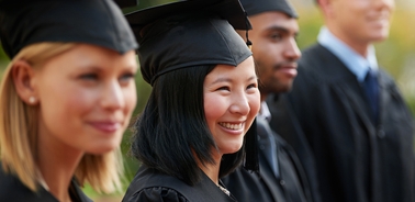 A group of happy graduates wearing caps and gowns at a graduation ceremony.
