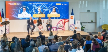 A panel discussion taking place in front of an audience, featuring three speakers at a conference.