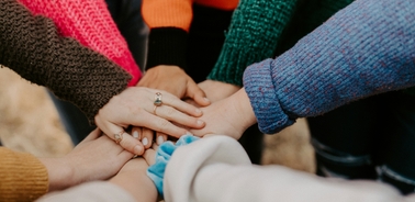 A close-up of a group of people stacking hands together, showing unity and teamwork.