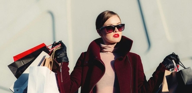A fashionable woman confidently carries shopping bags while wearing sunglasses.