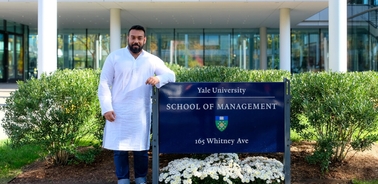 A person standing in front of the Yale University School of Management sign.