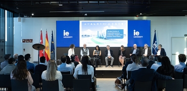 A panel discussion at IE University featuring several speakers and an engaged audience.