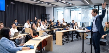 A speaker engages with an audience in a modern classroom setting.