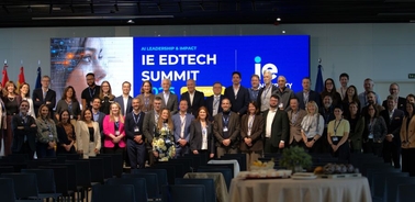 A large group of people gathered at the IE EdTech Summit with a presentation screen in the background.