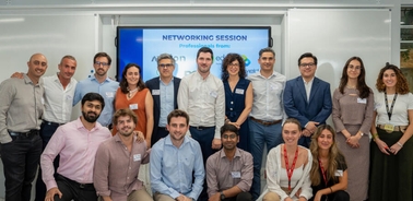 A group of professionals posing for a photo at a networking event with a sign in the background that reads 'NETWORKING SESSION'.