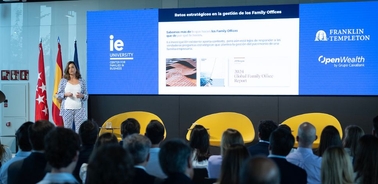 A speaker presents in front of an audience at a conference held at IE University.