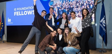 A group of happy individuals posing together in front of a presentation screen at an event.