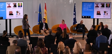 A business conference with multiple speakers presenting to an audience in a modern setting.