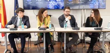 Four professionals seated at a conference table during a panel discussion.