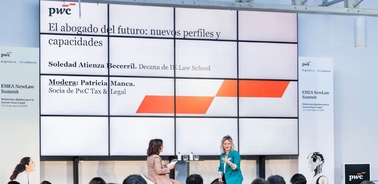 A panel discussion at an event featuring two women speaking on stage with a large screen behind them displaying information about the future of law careers.