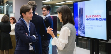 A networking event with participants discussing in front of a presentation screen.
