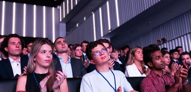 A group of people attentively watching an event in a conference hall.