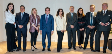 Eight professionally dressed individuals standing side-by-side in an indoor setting.