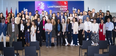 A large group of people posing for a photo at a conference event, with a banner in the background that reads 'LAWTOMATION DAYS'.