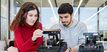 Two students are working together on a robotic project.