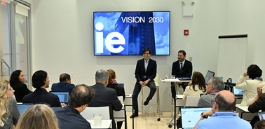 A panel discussion taking place with speakers in front of a presentation screen at an event themed 'Vision 2030'.