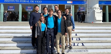 A group of young adults smiling in front of the Instituto Ferial de Vigo during a daytime event.