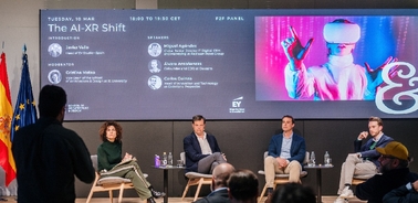 A panel discussion on AI and XR technologies featuring several speakers and an audience.