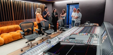 A group of people discussing in a modern recording studio.