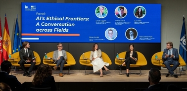 A panel discussion on AI's ethical frontiers at a conference, featuring five speakers sitting across the stage with a digital presentation behind them.